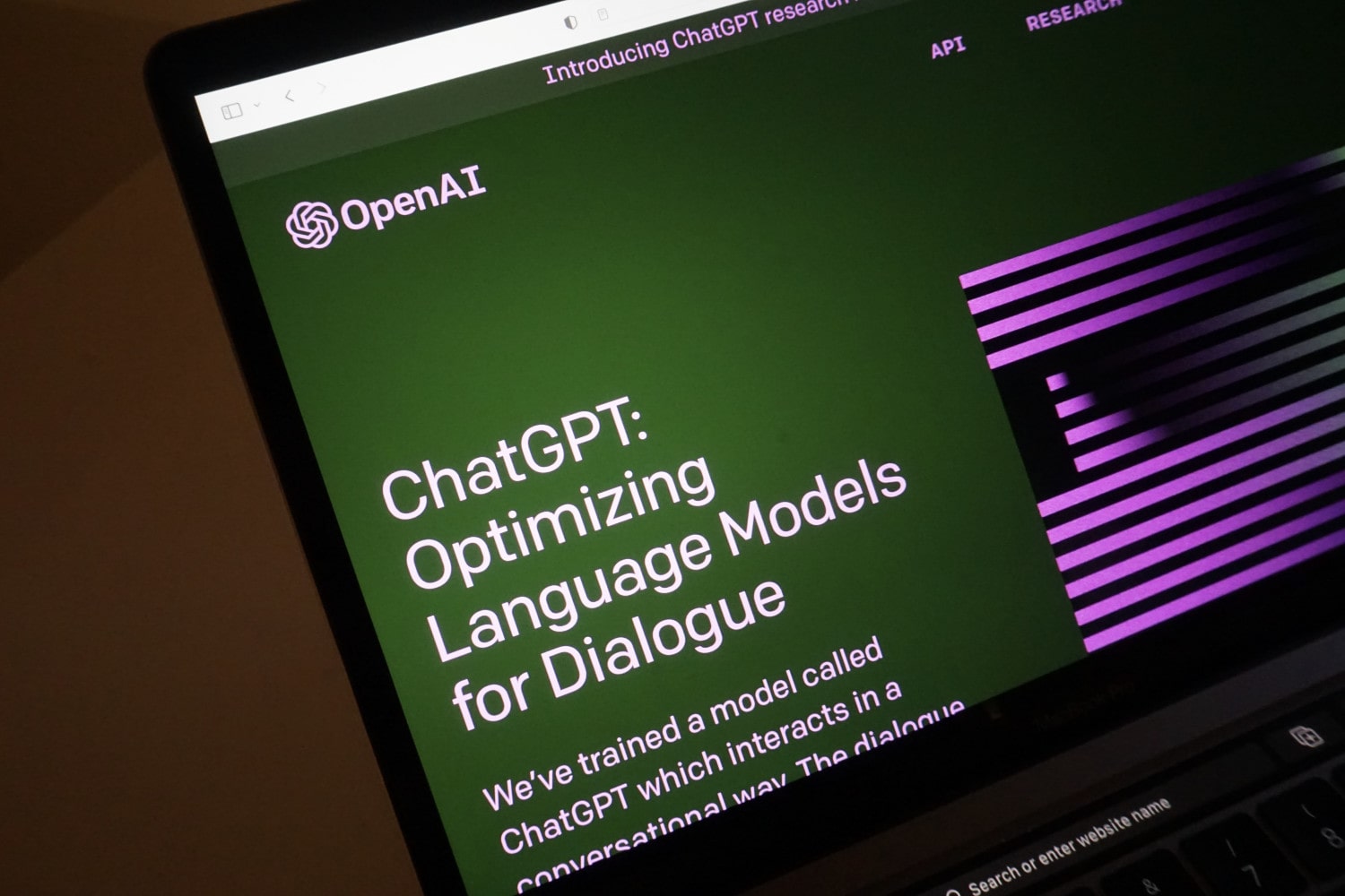 A laptop screen shows the home page for ChatGPT, OpenAI