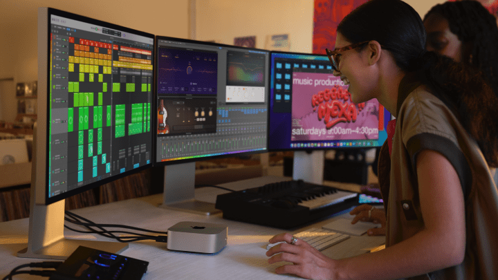 A woman using the M4 Mac mini with three monitors connected.