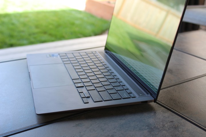 The Asus Zenbook S 14 on a table in front of a grass lawn.