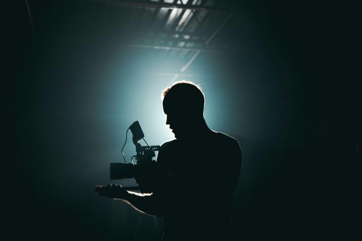 alt: A person holding a video camera in the dark, representing the potential downsides and ethical considerations surrounding AI in filmmaking.