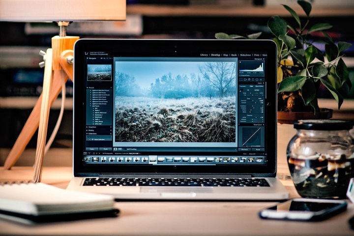 A Macbook sits on a desk with Adobe Lightroom opened on screen.