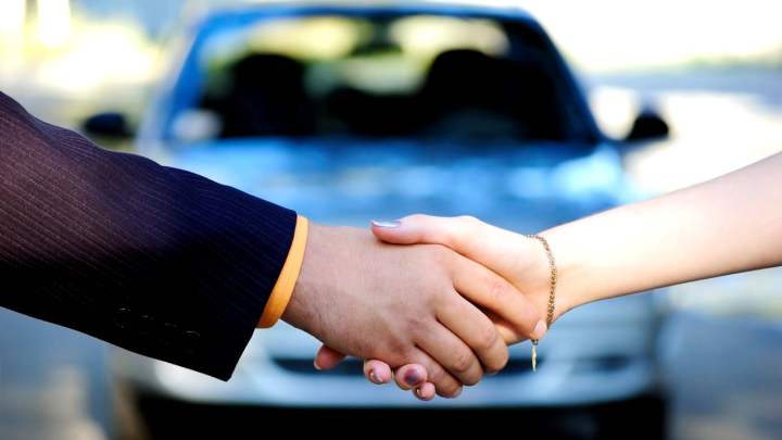 alt text:  A person signing the title of a car, transferring ownership.