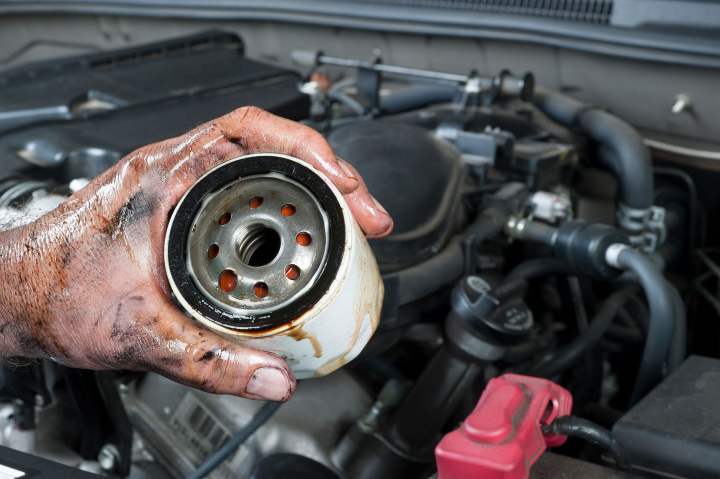 alt text: Removing an old oil filter from a car engine