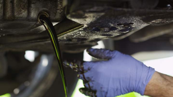 alt text: Draining old engine oil into a pan