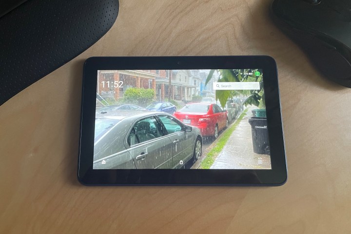 2022 amazon fire 7 laying on a desk next to a keyboard and mouse. Its display shows a rainy day.