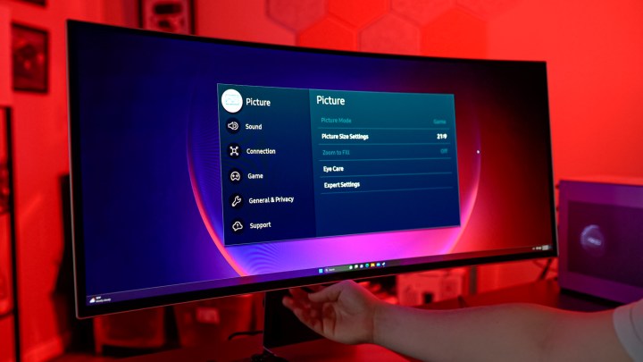 Alt: A hand using a remote to control the Samsung Odyssey OLED G8's interface and settings.