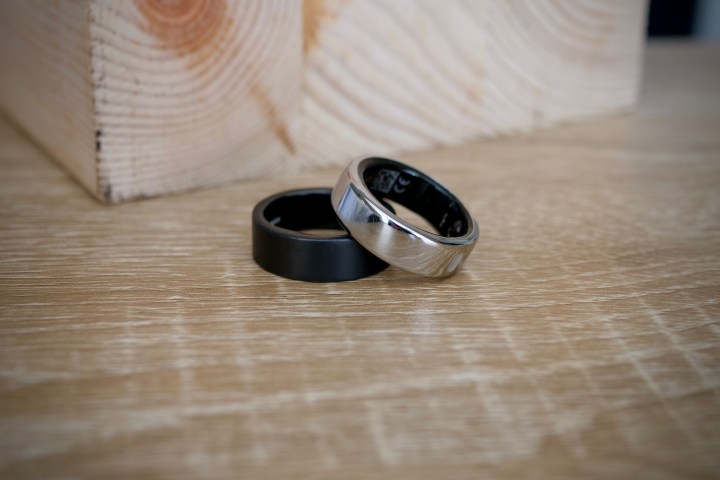 alt: The Oura Ring (silver) and Ultrahuman Ring Air (black) displayed on a table, emphasizing their contrasting aesthetics.