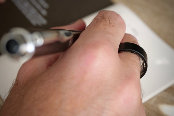 alt: A person wearing the Ultrahuman Ring Air while writing, demonstrating its discreet design and everyday usability.