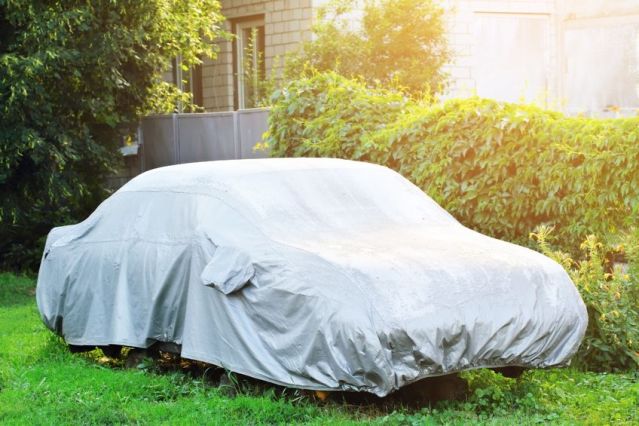 alt: A car covered with a car cover in a snowy driveway