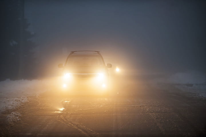 Car driving with low beams in snow