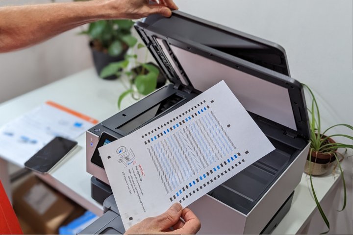 A person places the HP OfficeJet Pro 9015e alignment page in the scanner.