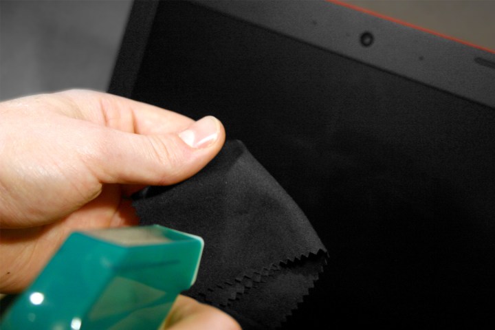 A person spraying a cleaning solution onto a microfiber cloth.