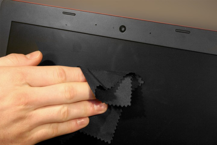 A close-up of a person cleaning a laptop screen.