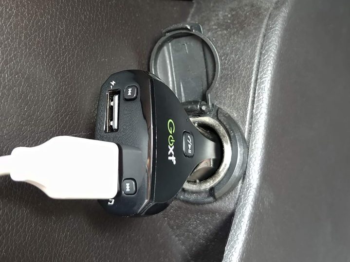 alt: A GOXT Bluetooth FM transmitter plugged into a car's cigarette lighter.