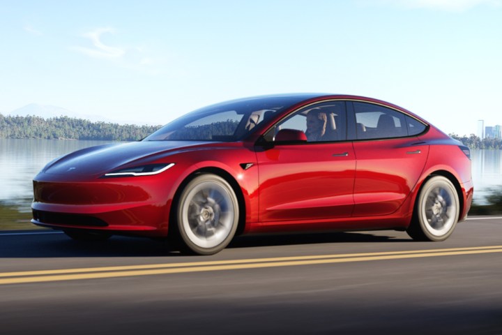 alt text: A person's hands holding the steering wheel of a Tesla, demonstrating how to press the scroll wheels for a system reset. 