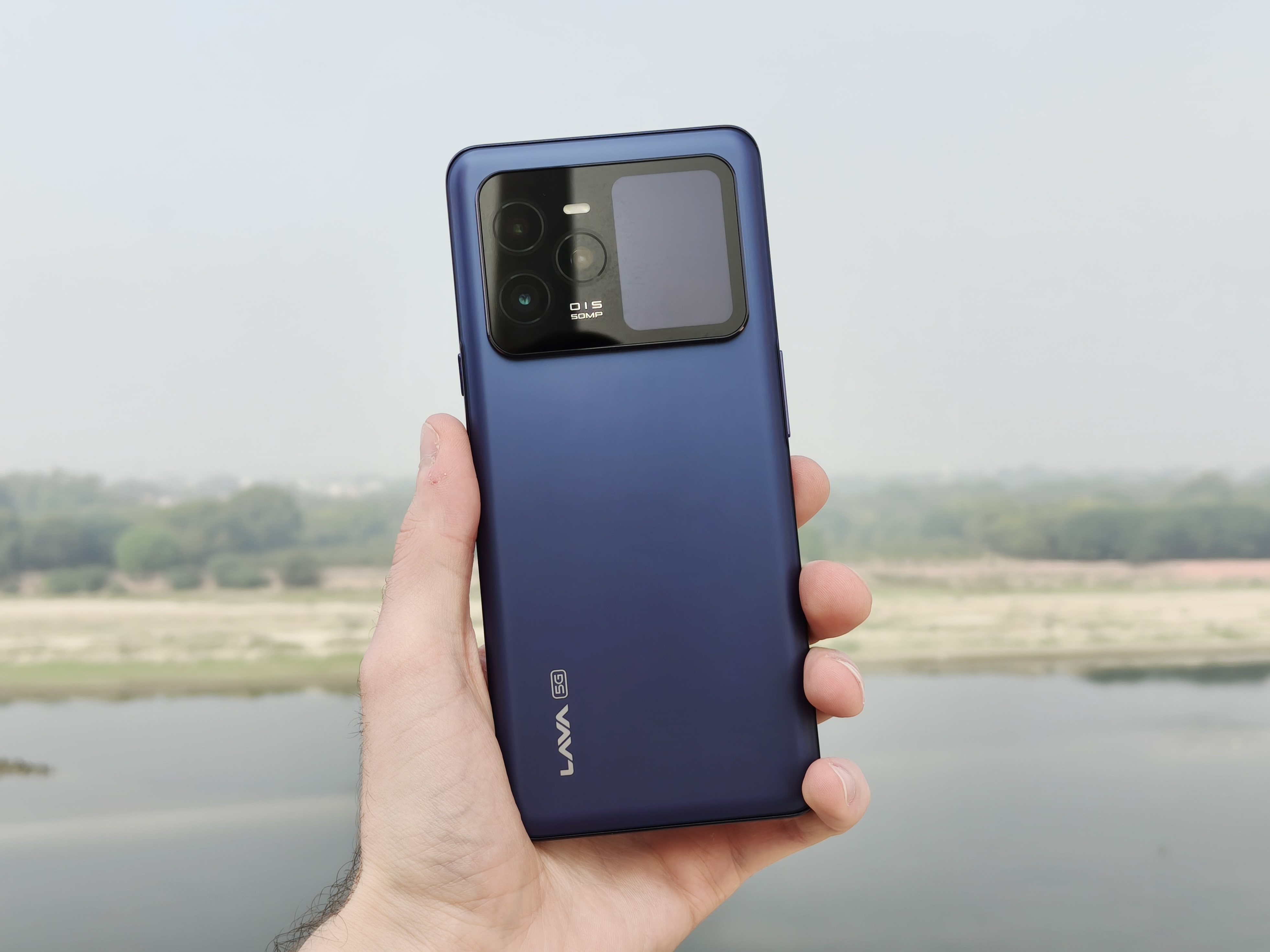 Alt: A person holding the Lava Agni 3, showcasing the phone's rear design, including the secondary display and camera module.