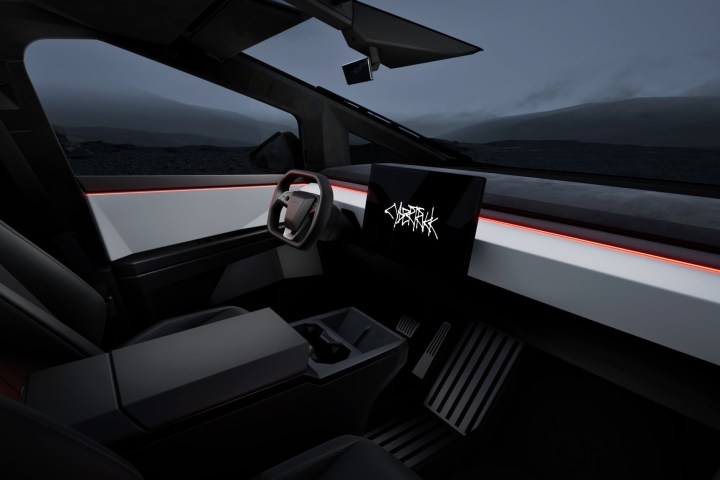 alt text: The interior of the Tesla Cybertruck featuring a minimalist design, a large central touchscreen, and a yoke steering wheel.