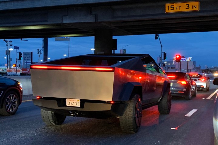 alt text: A Tesla Cybertruck being driven on a road, showcasing its real-world presence.