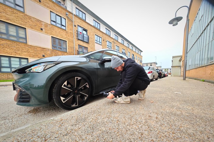 A person taking a photo of a car.