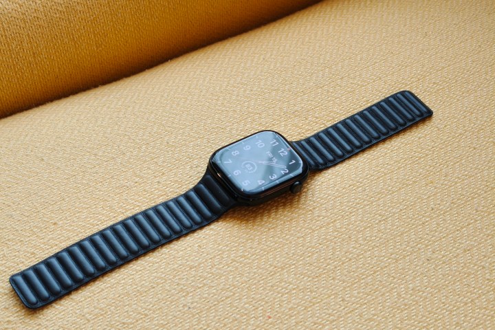 The Apple Watch Series 10, with a leather band, laying on a yellow chair.