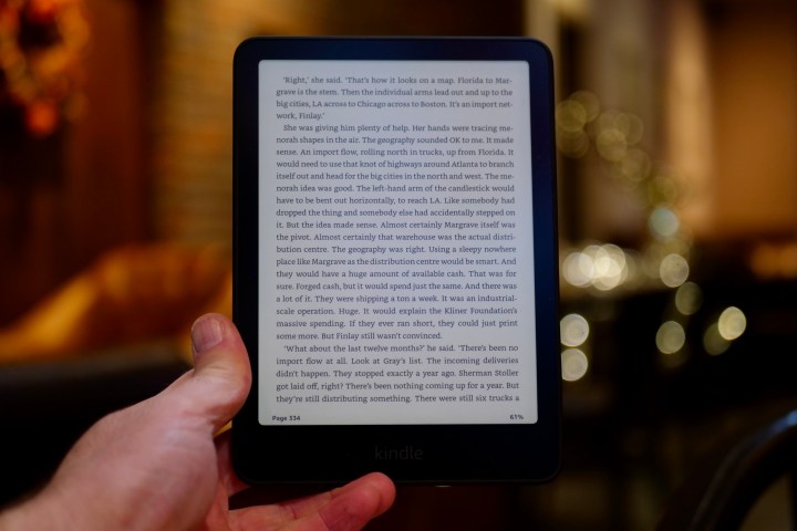 A person holding the Amazon Kindle Paperwhite 2024, showing a book on screen.