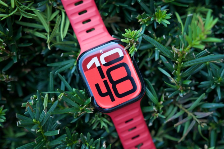 The Apple Watch Series 10 resting on a green bush.