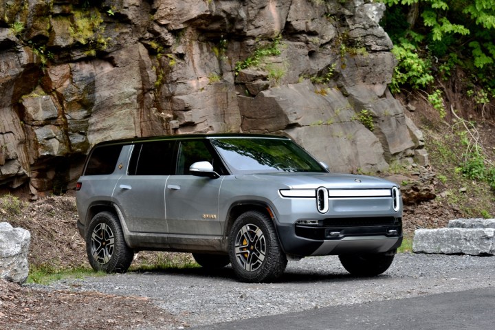 Alt: A 2022 Rivian R1S electric SUV parked against a rocky backdrop.