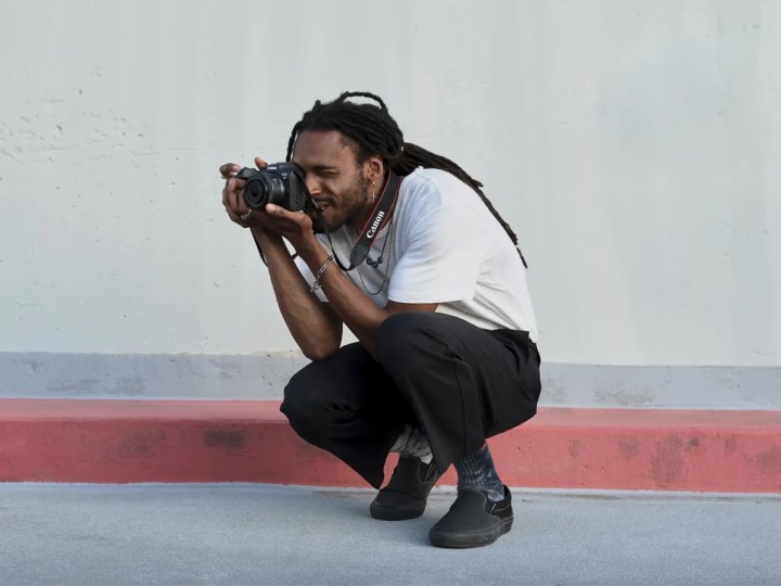 alt: A person takes a photo with a Canon EOS R7 mirrorless camera, demonstrating the integration of technology in filmmaking.