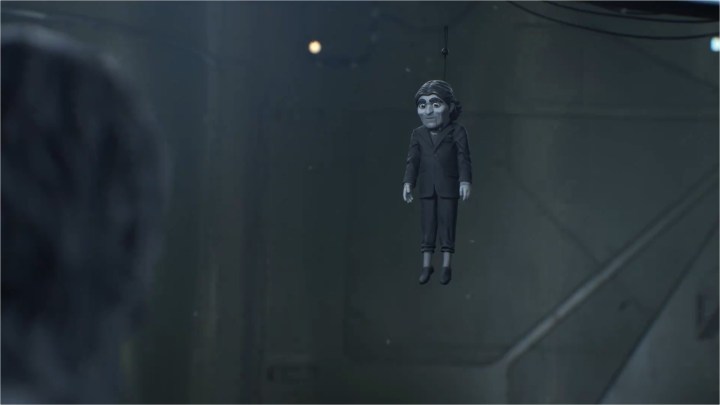 Dollman hanging from a ceiling and talking to Norman Reedus in Death Stranding 2.