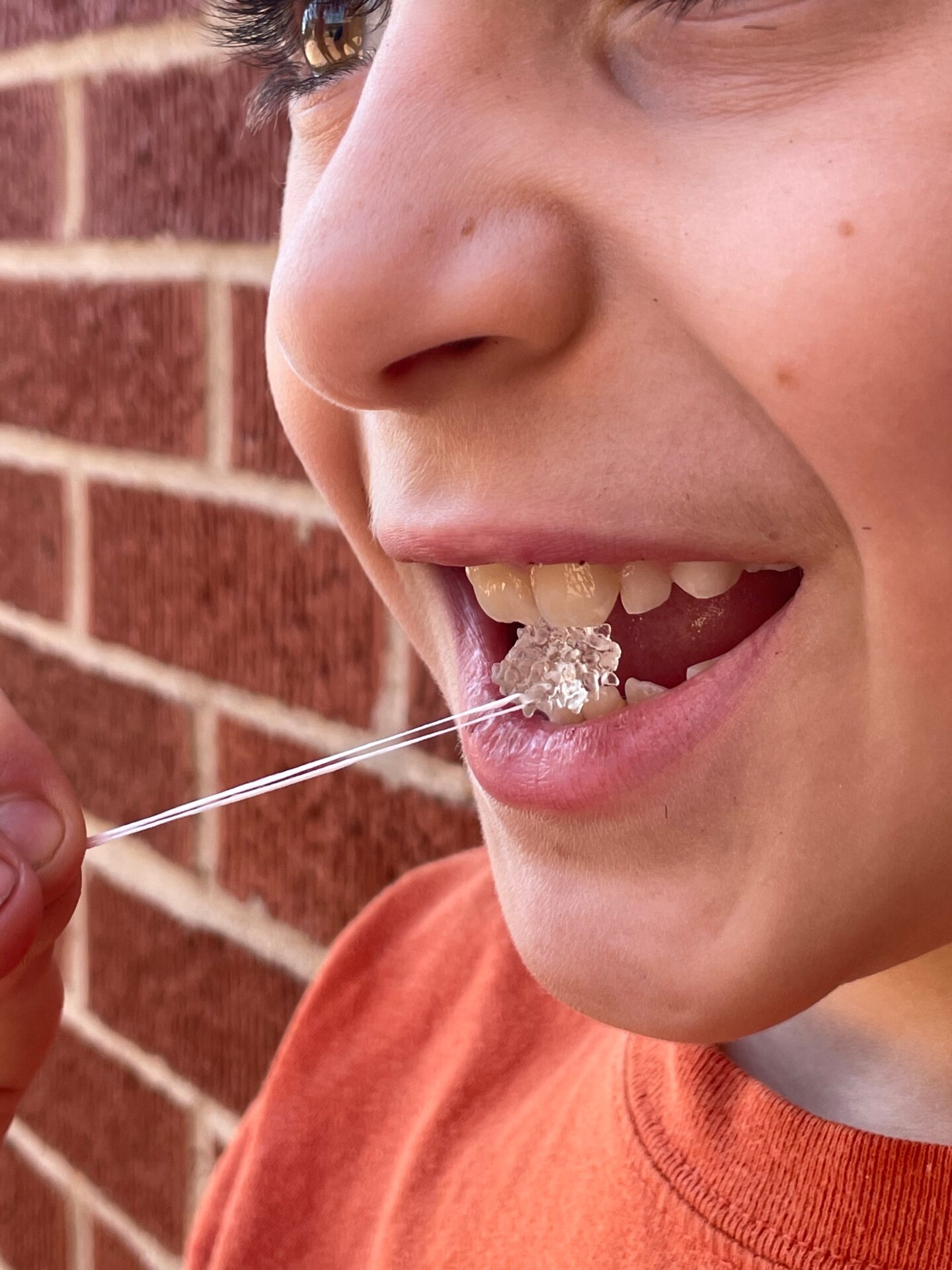 A student exploring a molecular model using their mouth. The attached string ensures safe handling.