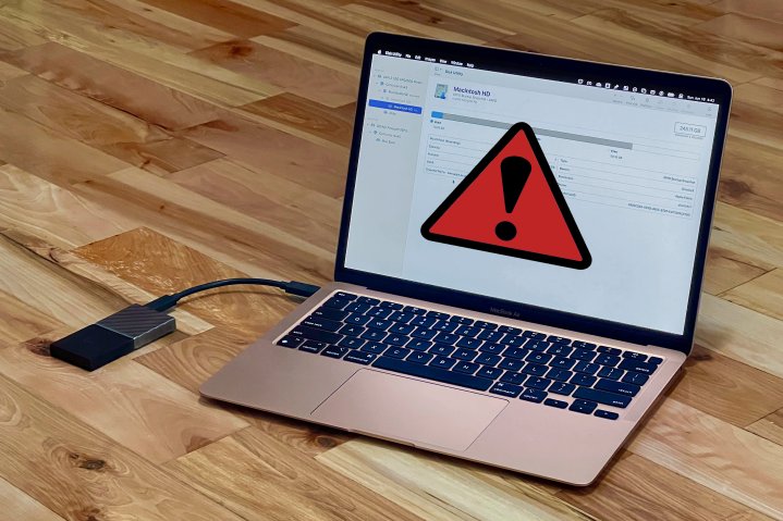 A rose gold MacBook Air has Disk Utility open with a red warning symbol and an external drive connected.