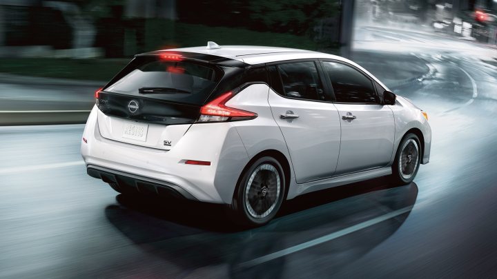 alt text: A 2023 Nissan Leaf driving on a wet city street.