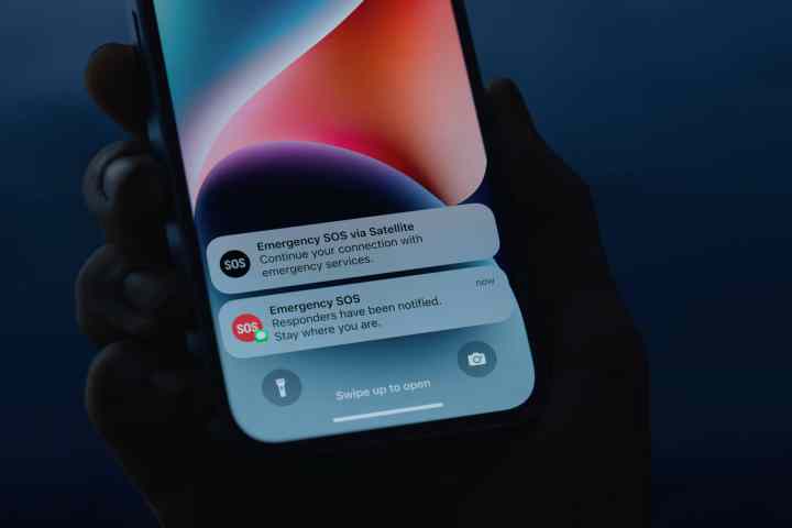 Person holding iPhone 14 with Emergency SOS via satellite notifications.
