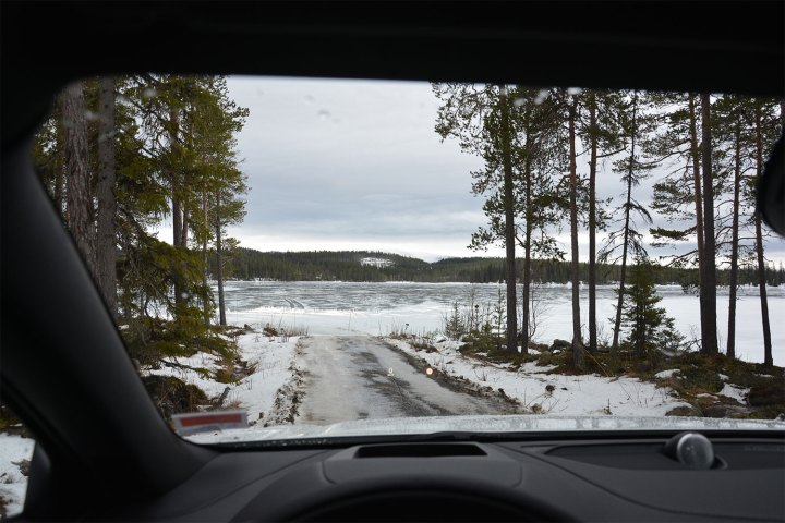 alt: Winter road with snow-covered trees and a car driving