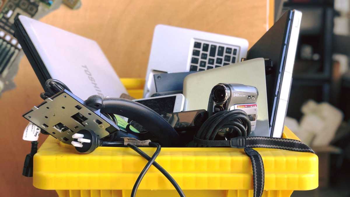 Alt: A laptop and other electronics are discarded in a recycling bin, highlighting the importance of responsible e-waste recycling.