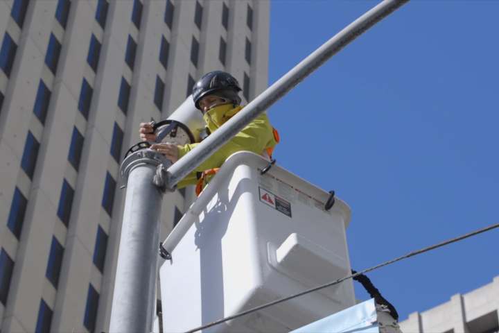 alt: A worker installing a 5G antenna on a building.