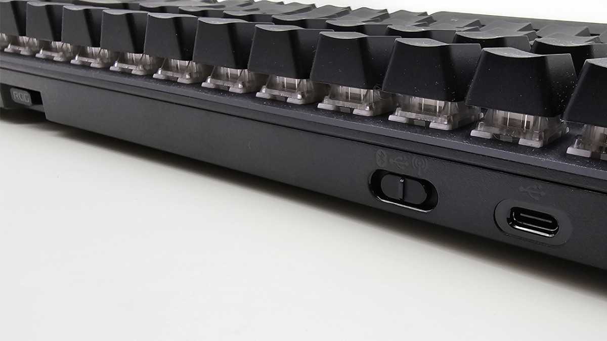 alt text: The back of the Asus ROG Strix Scope II 96 Wireless keyboard showing the switch for toggling between different operating modes.