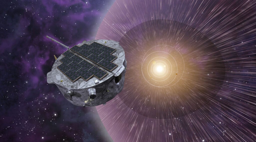 alt text: An artist's depiction of the IMAP spacecraft in space. The spacecraft is shown with its solar panels deployed and antennas extended, against a backdrop of stars and the faint glow of the heliosphere.