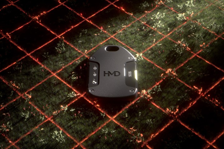 alt: The HMD OffGrid resting on grass, surrounded by laser beams, highlighting its rugged design.