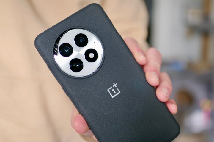 A person holding the OnePlus 13, showing the wireless charging insert in the camera cutout.