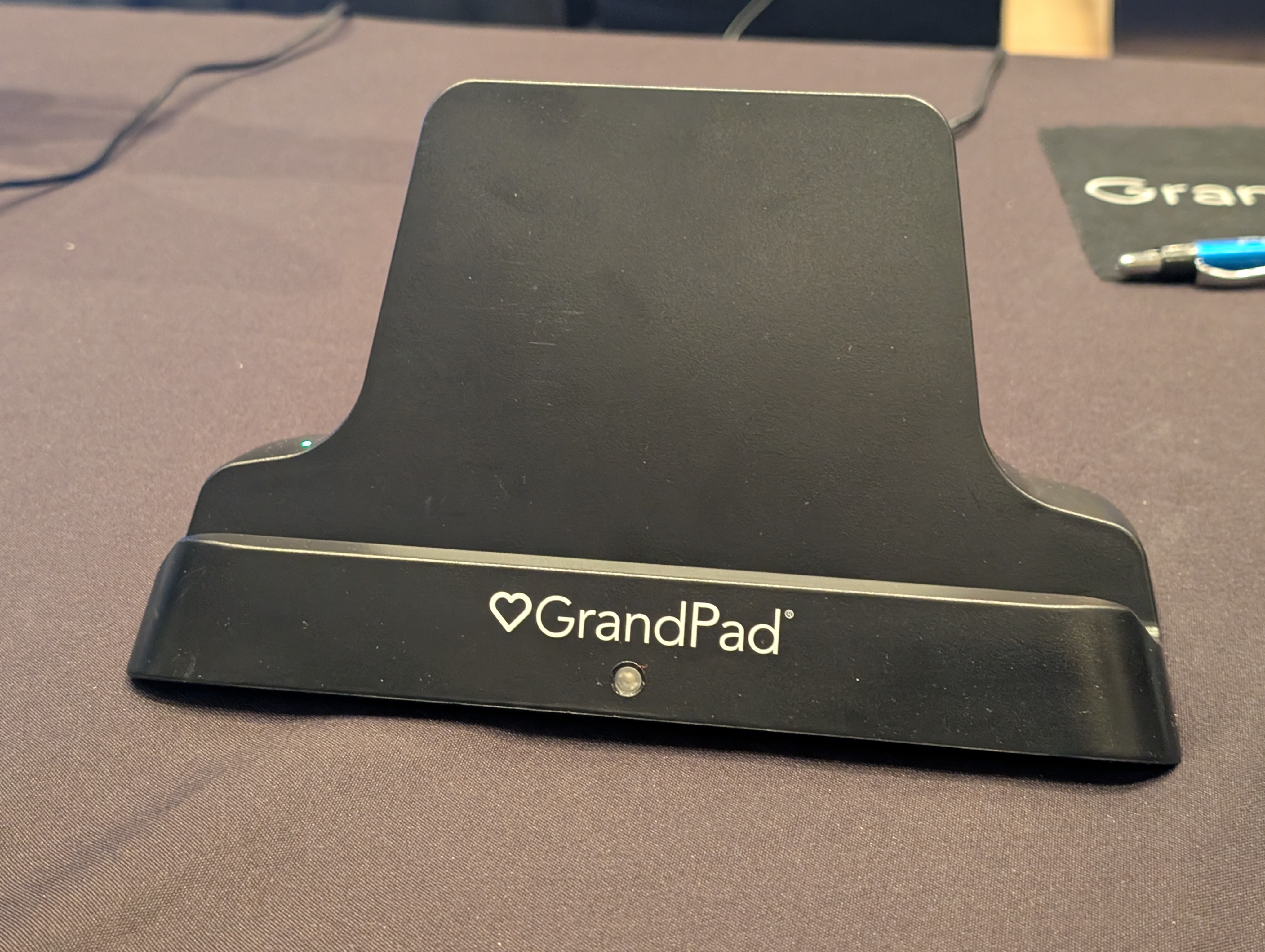 alt: The GrandPad resting on its wireless charging stand, demonstrating the ease of use and convenience for seniors.