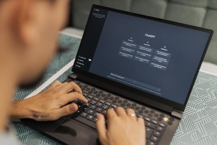 alt text: A person typing on a laptop displaying the ChatGPT website.