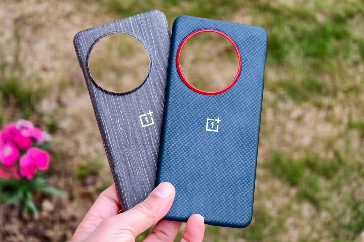 OnePLus 13 official Aramid Fiber and Wood Grain cases held in hand.