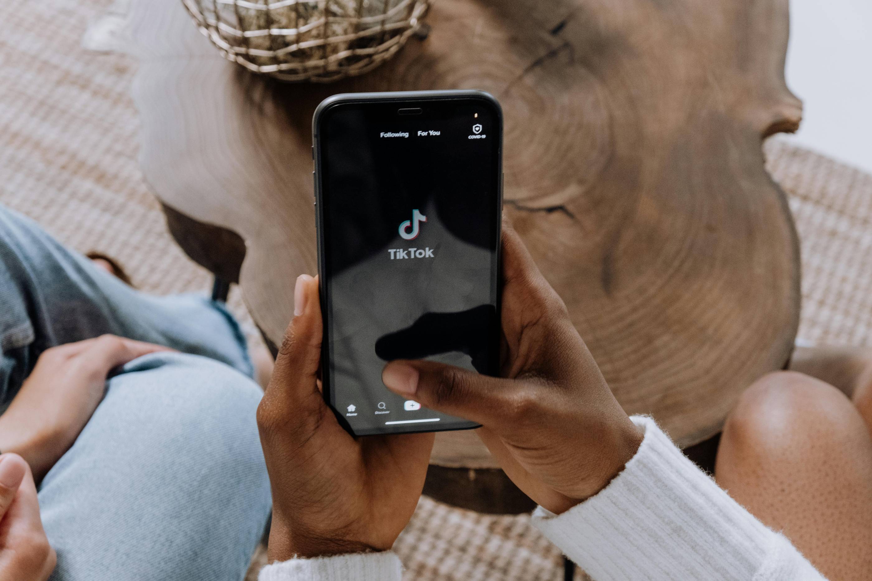 alt text: A person holding a smartphone displaying the TikTok app interface.