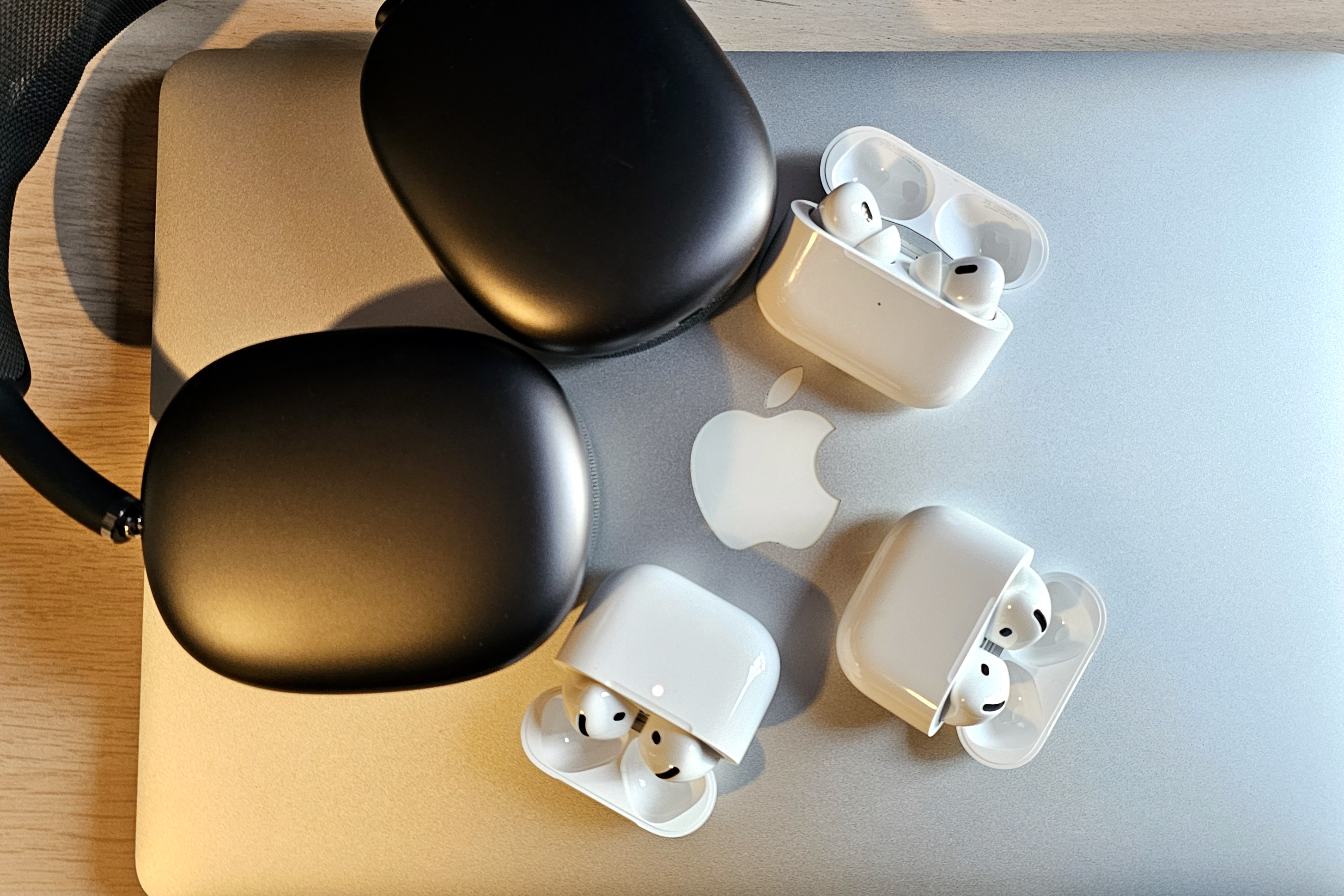 Apple AirPods and AirPods Max sitting on the lid of a MacBook Pro laptop.