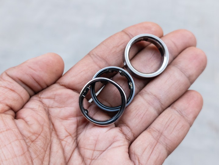 Alt: Three smart rings, the Oura Ring 4, Galaxy Ring, and RingConn Gen 2, displayed in the palm of a hand.