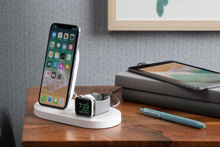 Photo shows a Belkin Boost Up Wireless Charging Dock with an Apple iPhone and Apple Watch docked, on a nightstand