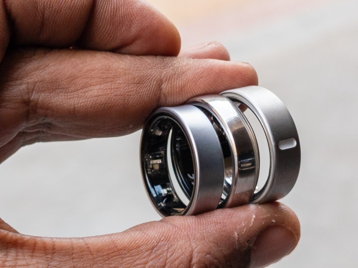 Alt: Three smart rings, the Oura Ring 4, Galaxy Ring, and RingConn Gen 2, held between two fingers.