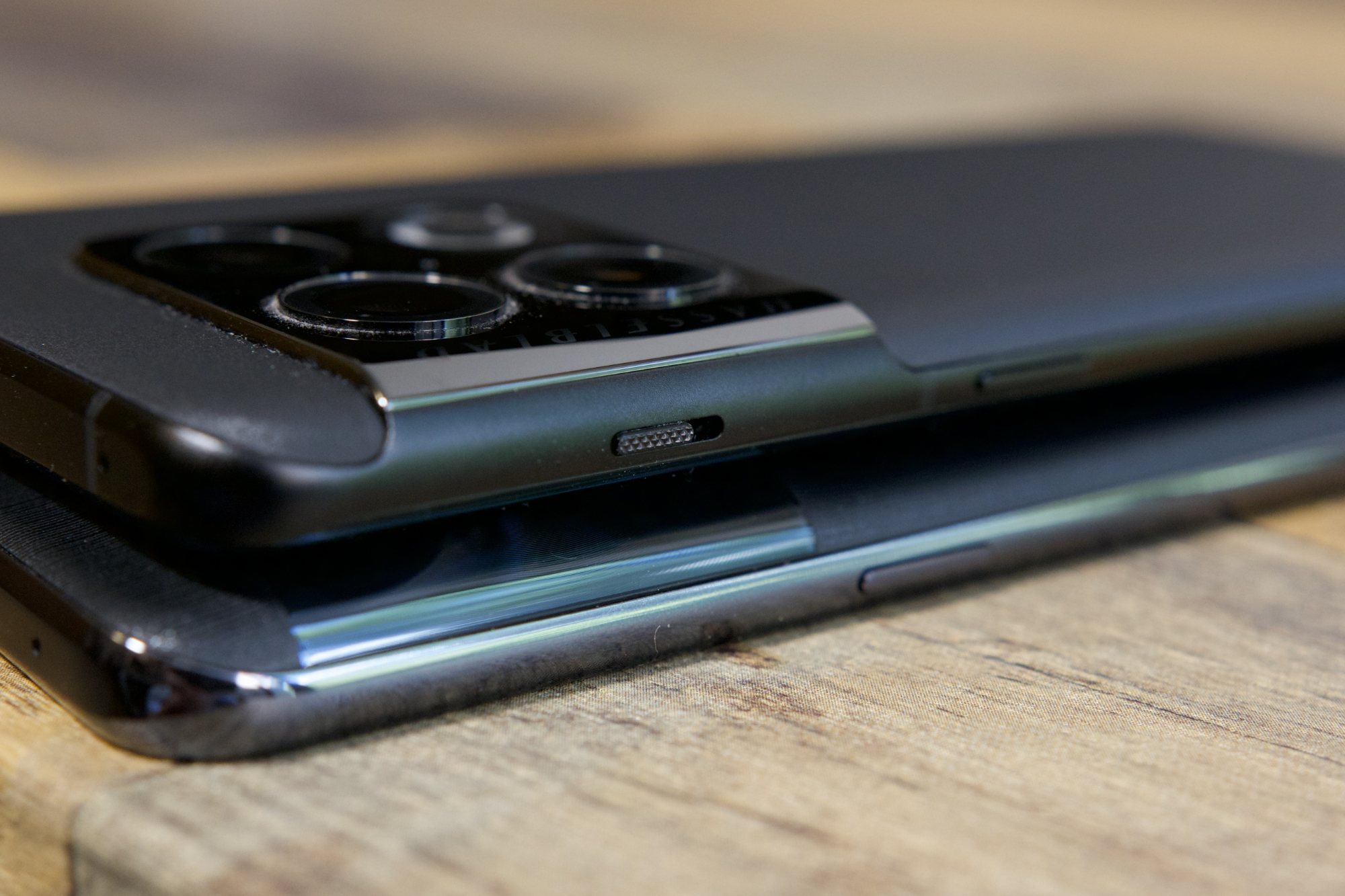 Alternative text: The OnePlus 10T and OnePlus 10 Pro side by side on a wooden desk.
