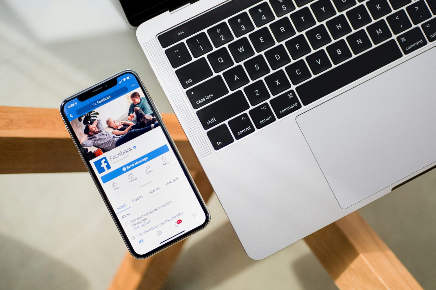 alt: An iPhone displaying the Facebook app placed next to a MacBook.